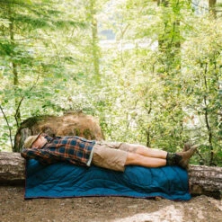 Rumpl The Original Puffy Blanket Turpledd (Deepwater) -Osprey || Icebreaker || Patagonia Butikk Rumpl The Original Puffy Blanket Turpledd Deepwater modell sover ute